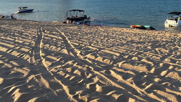 Uma praia com barcos e um afloramento rochoso ao fundo.