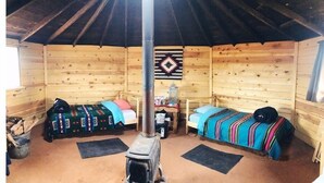 Uma cabana aconchegante com duas camas de madeira, uma mesa central e um enfeite decorativo na parede.