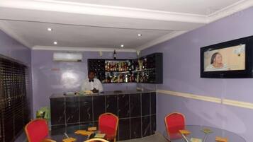 Un espace bar avec un barman, un écran de télévision et un coin salon avec des chaises et une table.