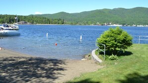 Un llac amb una barca amarrada a l'esquerra, envoltat de vegetació i turons al fons.