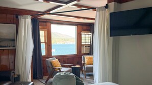 Habitació d'estil cabana amb llit, dues cadires, televisió i finestra amb vista a un llac.