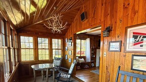 Un interior de fusta amb una taula de dinar, cadires, un candelabrum i quadres amb marc a les parets.
