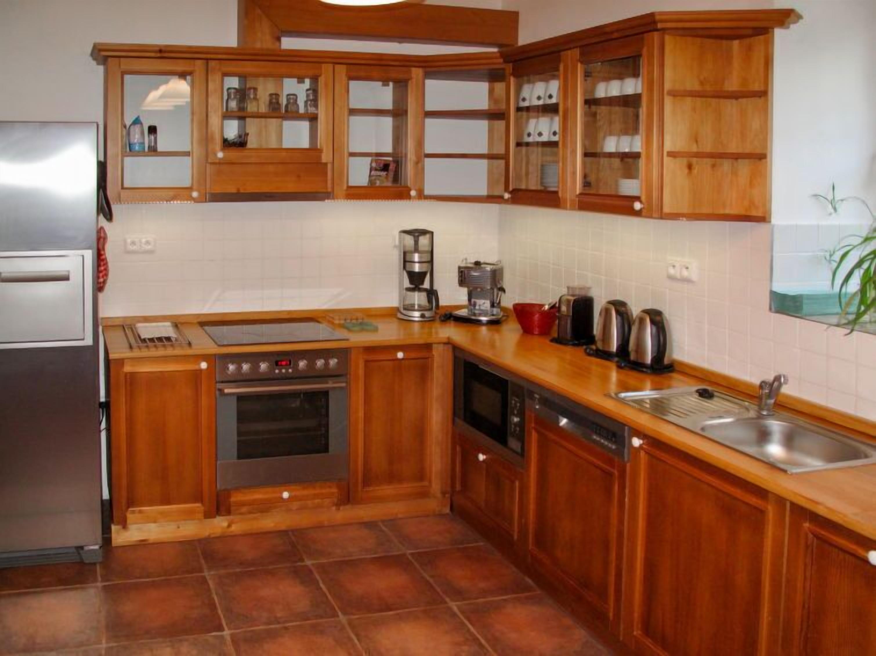 A kitchen with wooden cabinets, a stainless steel refrigerator, a stove, an oven, a dishwasher, and a sink.