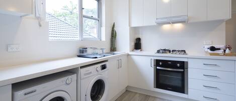 Cozinha moderna com máquina de lavar integrada, forno e janela que oferece iluminação natural.
