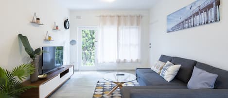 Un salon moderne avec un canapé, un téléviseur et des plantes décoratives.