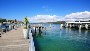 A wooden pier extending into a clear blue body of water with boats docked nearby. - Lotus Stay Manly Apartment 29B (Manly)