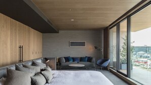 A modern bedroom with a large bed, a sofa, and a chair. There is a window with a view of buildings outside. - Hotel Canata Kyoto (Kyoto)