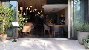 A modern restaurant with a long counter, multiple seating areas, and hanging pendant lights. - Hotel Canata Kyoto (Kyoto)