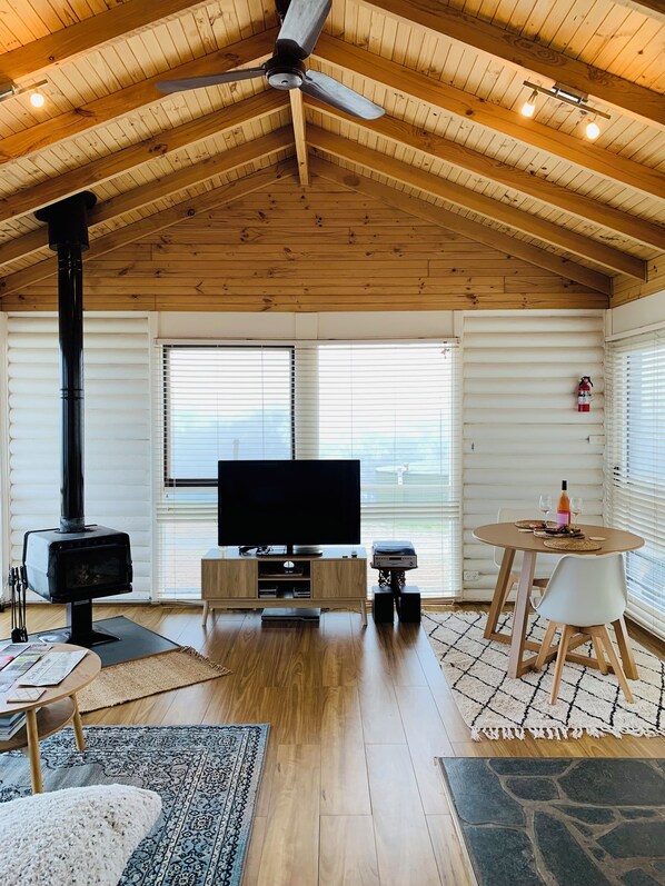 Un acogedor interior de cabaña con techo de madera, chimenea, televisión y comedor.