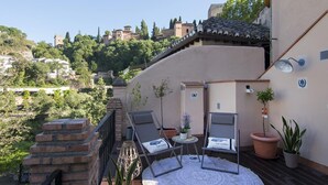 Una terraza en la azotea con dos sillones, una mesita y plantas en macetas.