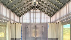 A large, industrial-style room with a metal roof, two large doors, and a black mat at the entrance.