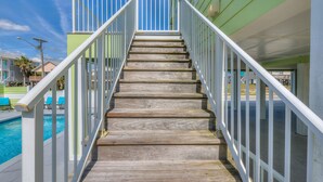 A wooden staircase with white railings leading to a pool area. - Sea Urchins, Unit 2. 5 BR. Beachview. The Beach, so close, for less! Pool. (Gulf Shores)