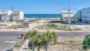 A coastal road with a stop sign, beach houses, and a clear view of the ocean. - Sea Urchins, Unit 2. 5 BR. Beachview. The Beach, so close, for less! Pool. (Gulf Shores)