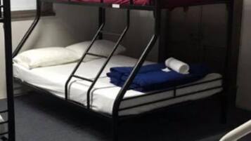A bunk bed with a mattress, pillows, and a blanket.