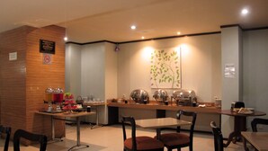A modern restaurant with a wooden counter, buffet area, and seating arrangement. - Hotel Alma (Jakarta)
