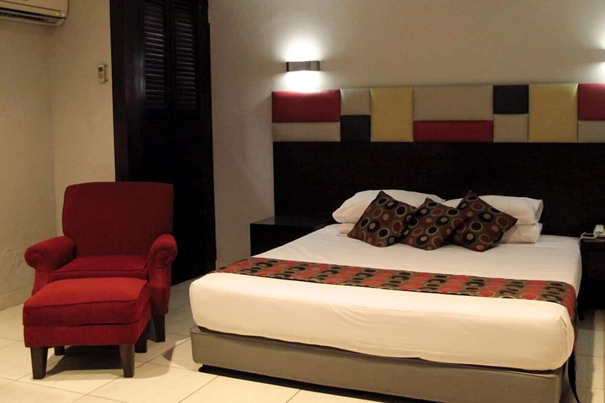 Une chambre d’hôtel avec un lit, un fauteuil rouge et une table de chevet.