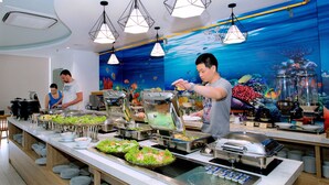 A buffet setup with various food items and a decorative underwater mural in the background.