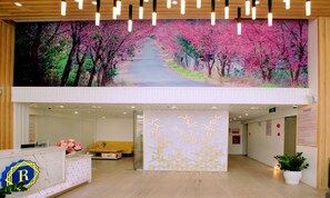 Welcome to the reception area, featuring a stylish desk with a geometric pattern and a digital screen showcasing a serene outdoor scene.