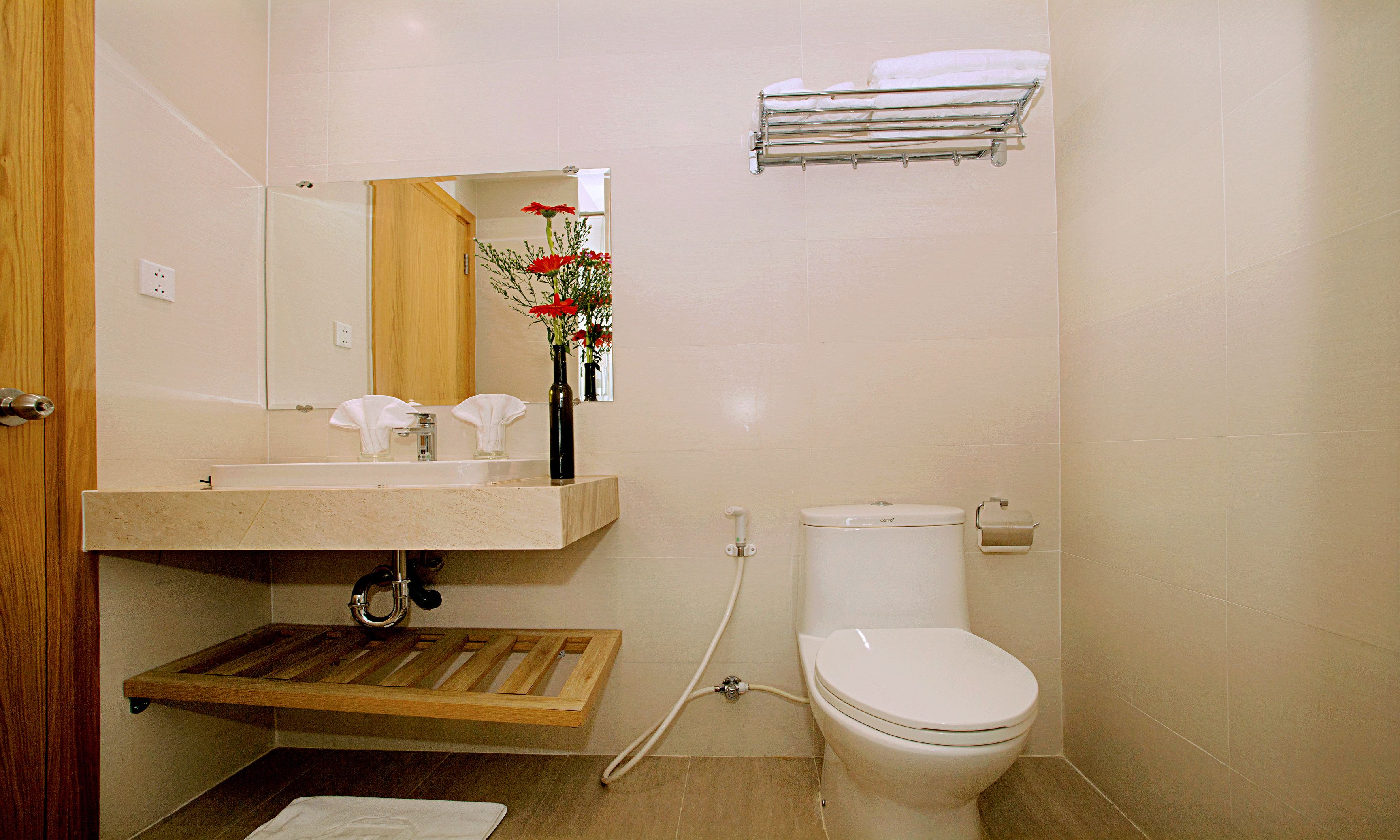 A bathroom with a wooden vanity, a toilet, and a towel rack.