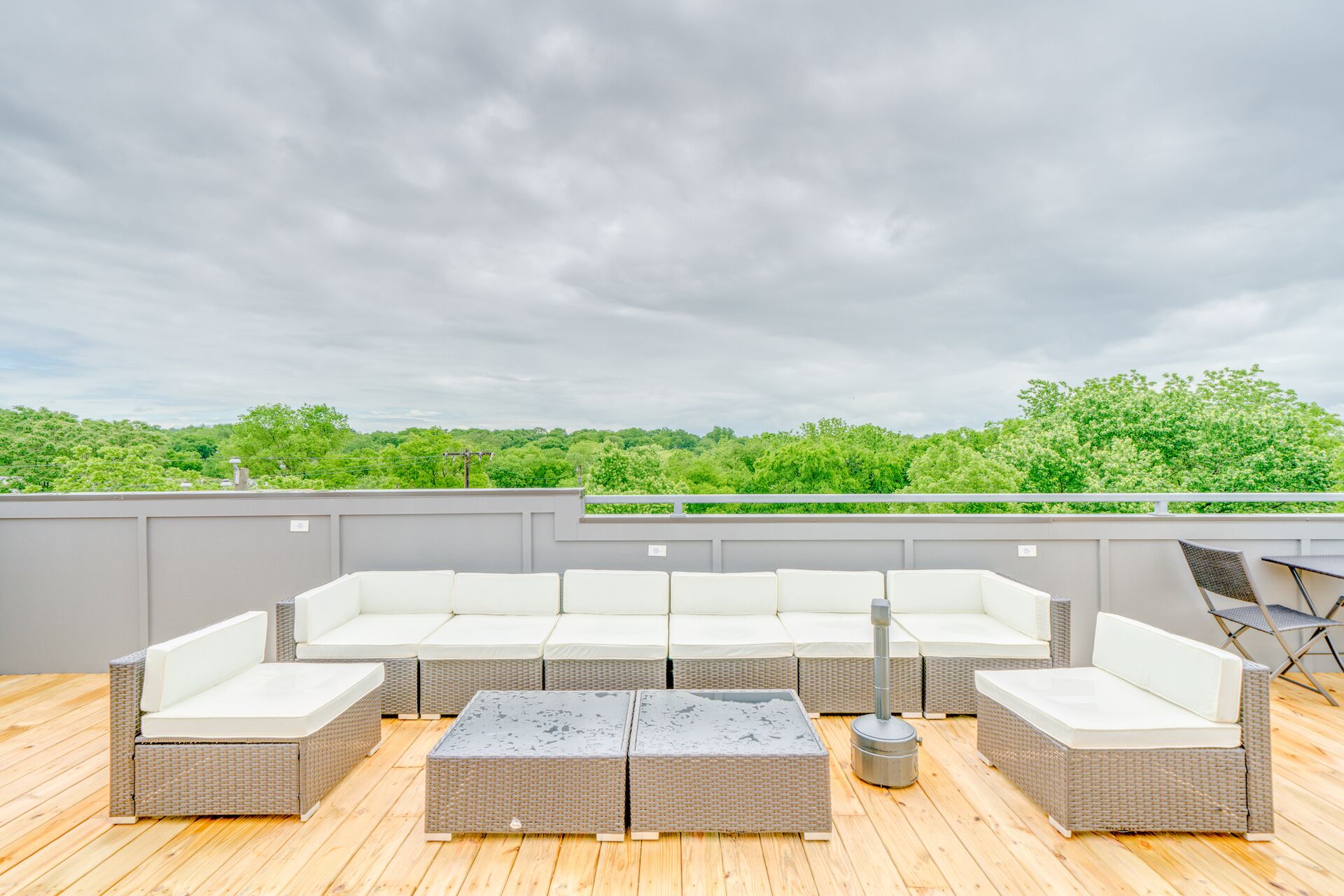 A rooftop patio with a sectional sofa, a coffee table, and a small table with chairs.