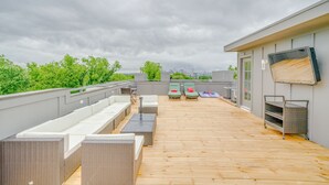 Terraza en la azotea con mobiliario exterior, un televisor y vistas del horizonte de la ciudad.