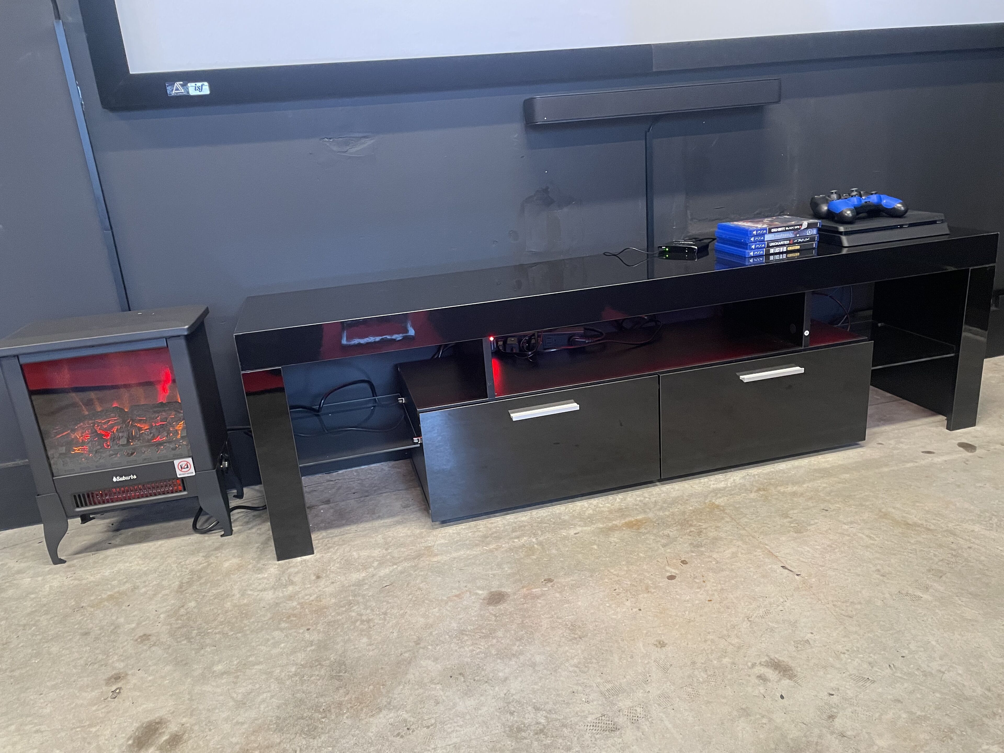 Un mueble de entretenimiento negro con televisor, reproductor de DVD y control de videojuegos.