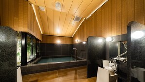 Een moderne badkamer met een houten plafond, een badkuip, een douchegedeelte en een toilet.