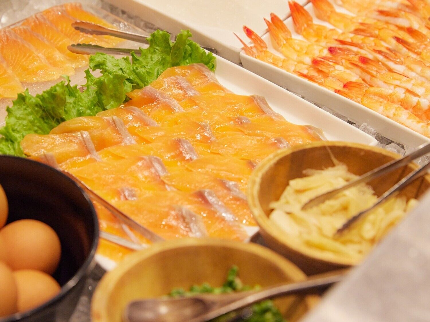 A buffet with various food items including salmon, shrimp, and vegetables.