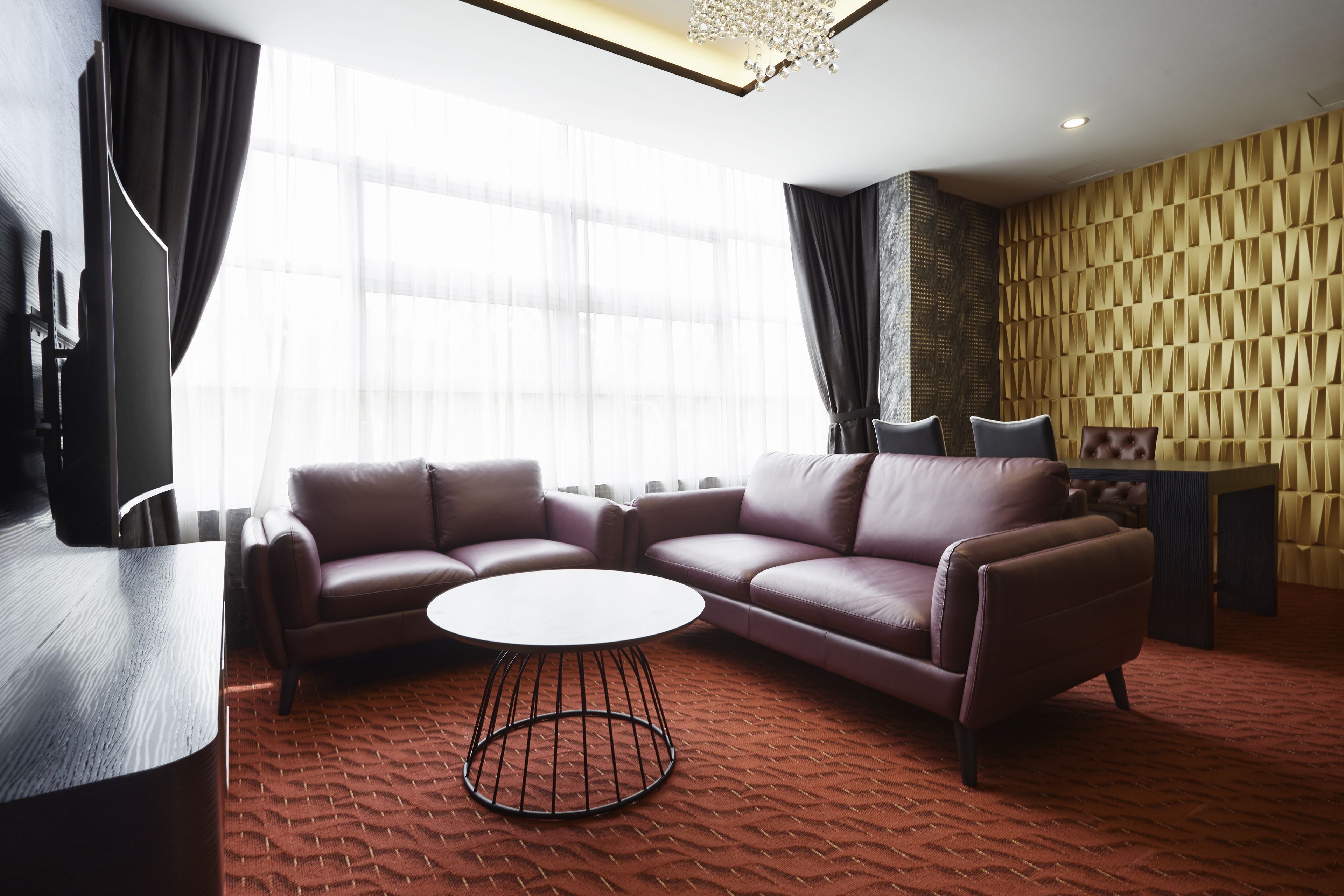 Una sala de estar moderna con un sofá modular, una mesa de centro redonda y un televisor sobre un mueble.