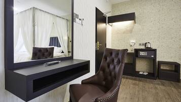 Una habitación de hotel moderna con un espejo grande, un sillón de cuero marrón, una mesita de noche y un televisor montado en la pared.