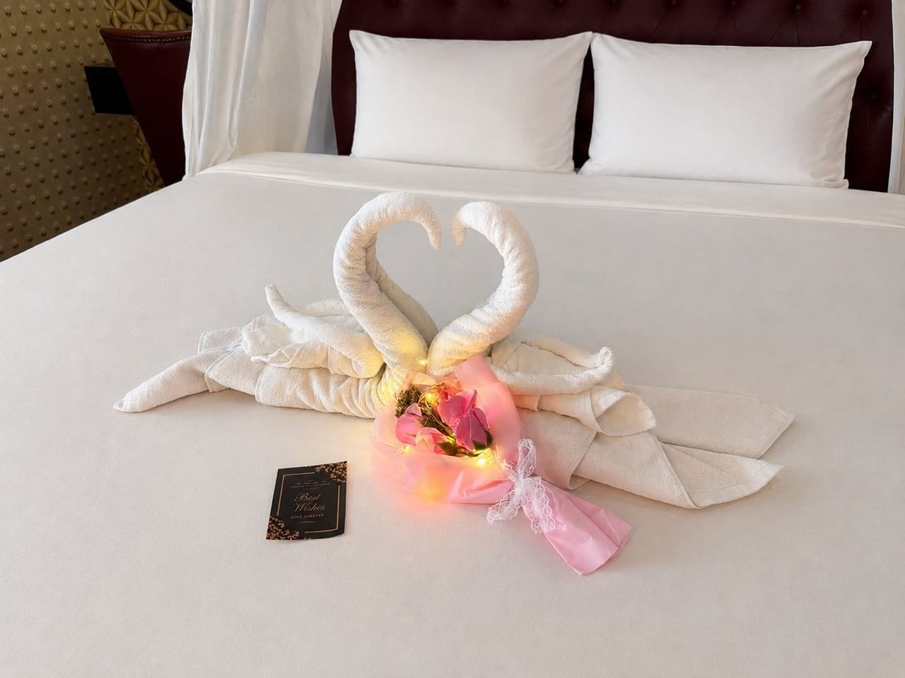 Una cama con una composición decorativa de toallas y flores.
