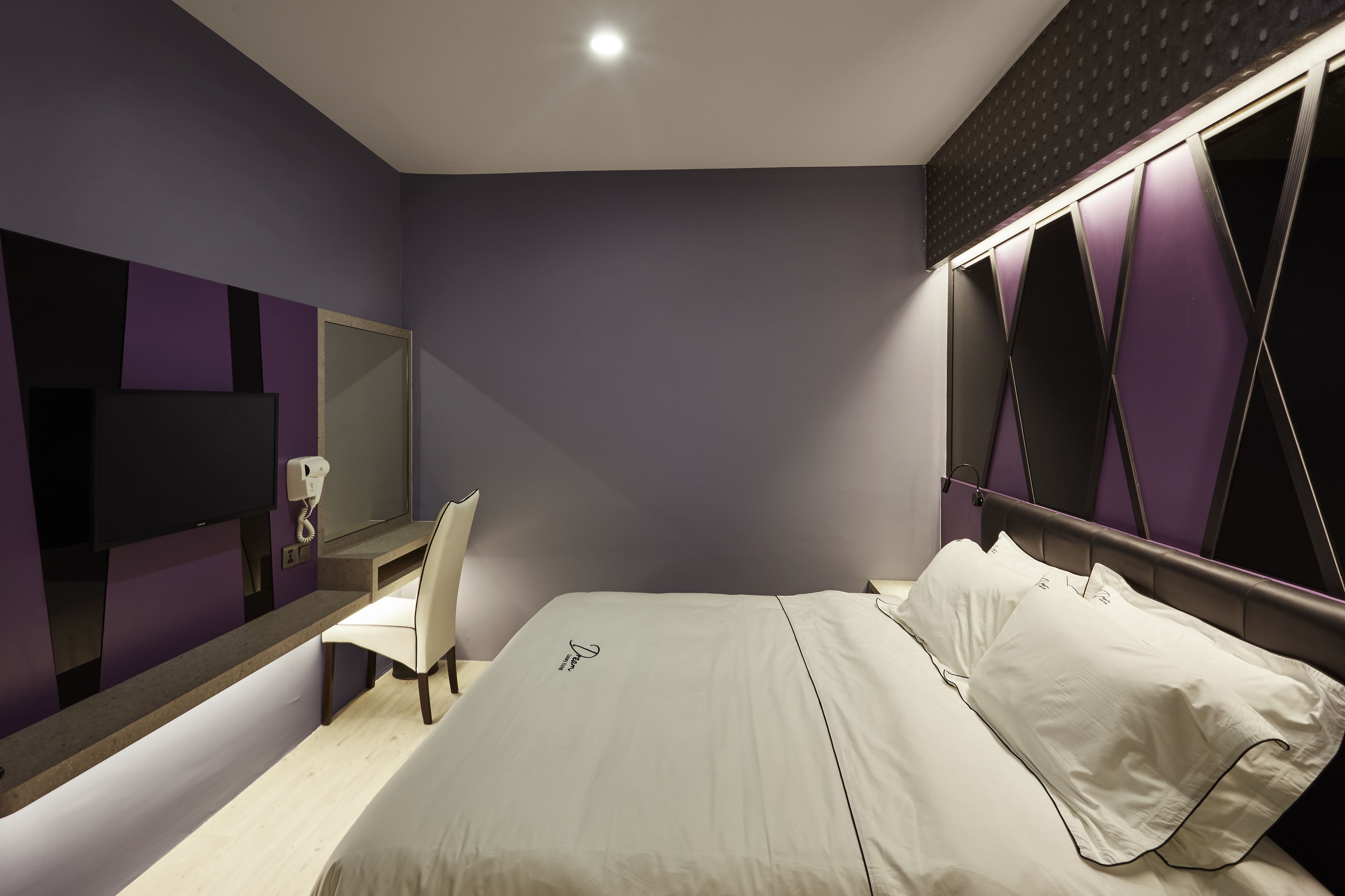 Une chambre d’hôtel moderne équipée d’un lit, d’un bureau, d’une chaise et d’un grand miroir.