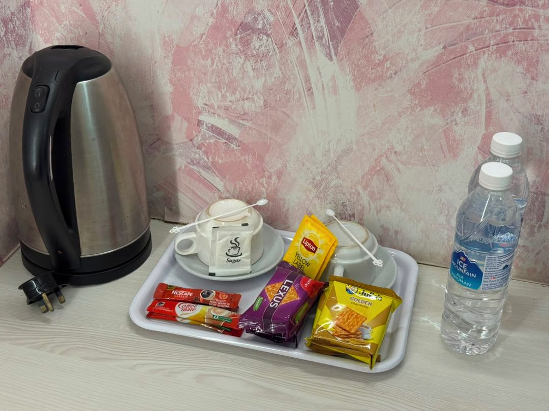 Bandeja con tetera, sobre de azúcar, leche condensada, café instantáneo y botella de agua.