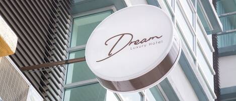 Señal para el Hotel Dream Luxury, con la fachada moderna de un edificio al fondo.
