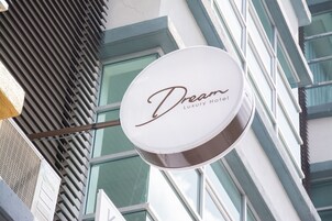 Señal para el Hotel Dream Luxury, con la fachada moderna de un edificio al fondo.