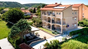 A multi-story building with a courtyard, surrounded by greenery and hills.