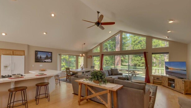 A spacious living area with a large window, a ceiling fan, and a television.