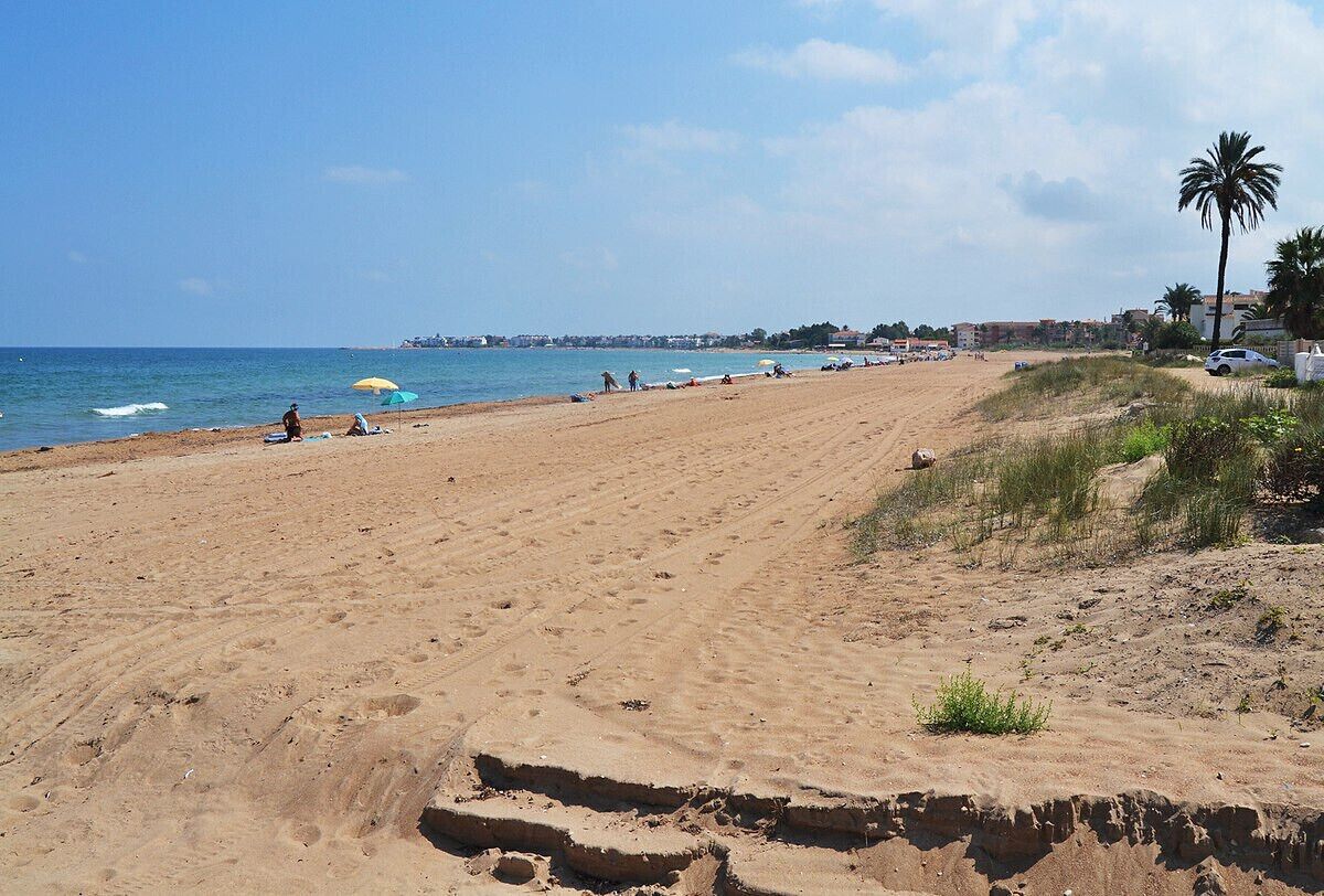 A sandy beach with umbrellas and people.