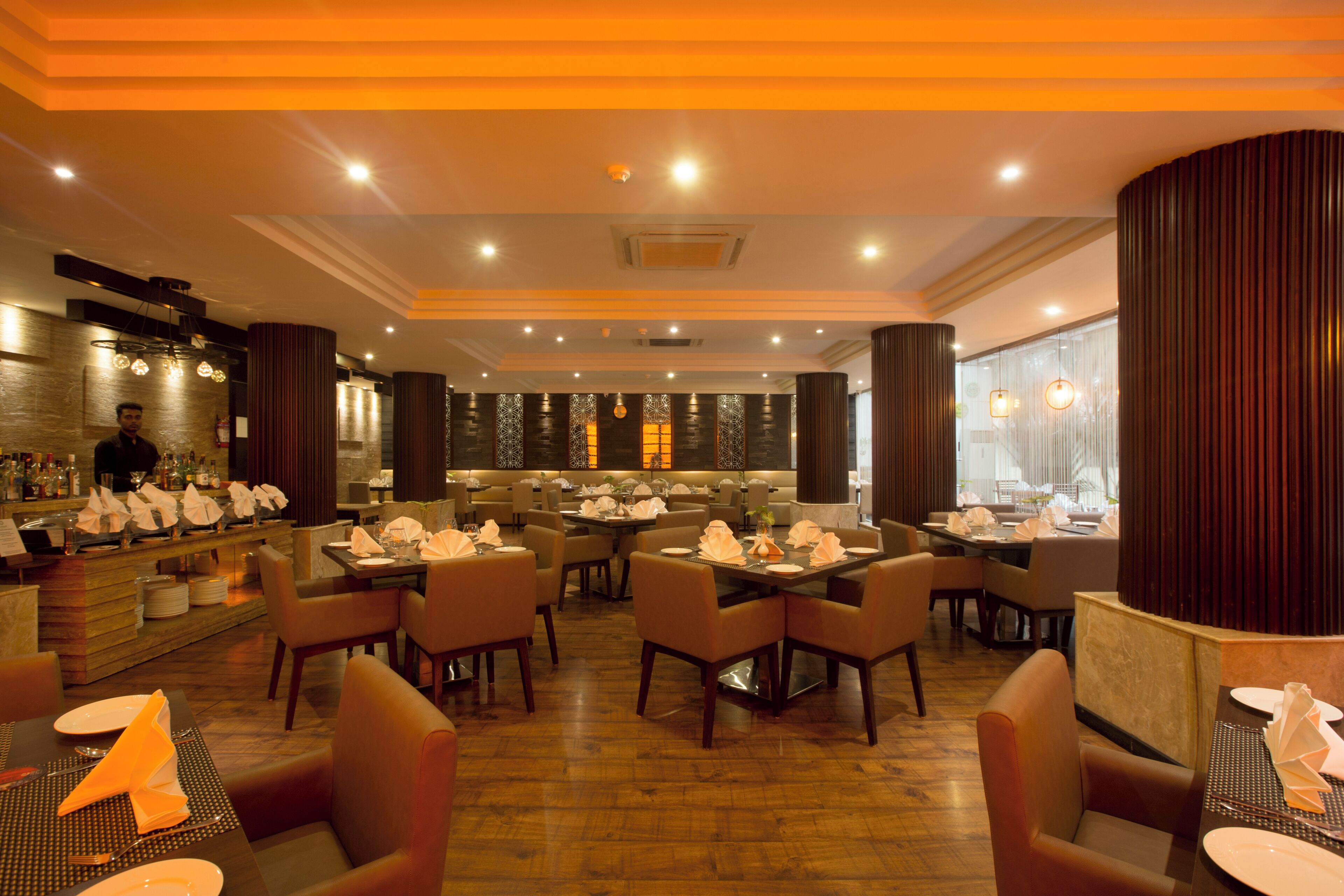 A restaurant with multiple tables and chairs, a bar area with bottles and glasses, and a modern interior design.