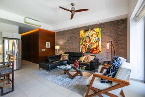 A modern living room with a sectional sofa, a coffee table, and a large abstract painting on the wall.