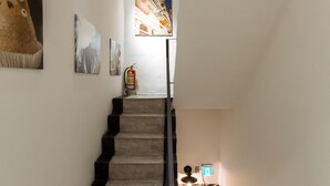 Una escalera con barandilla, un extintor y un accesorio de luz fijado a la pared.