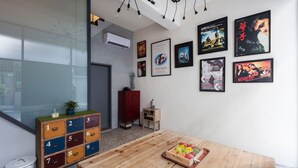 Una habitación moderna con una mesa de madera, un mueble de almacenamiento colorido y carteles de películas en la pared.