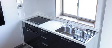 Una cocina moderna con ventana, estufa integrada y un lavamanos.