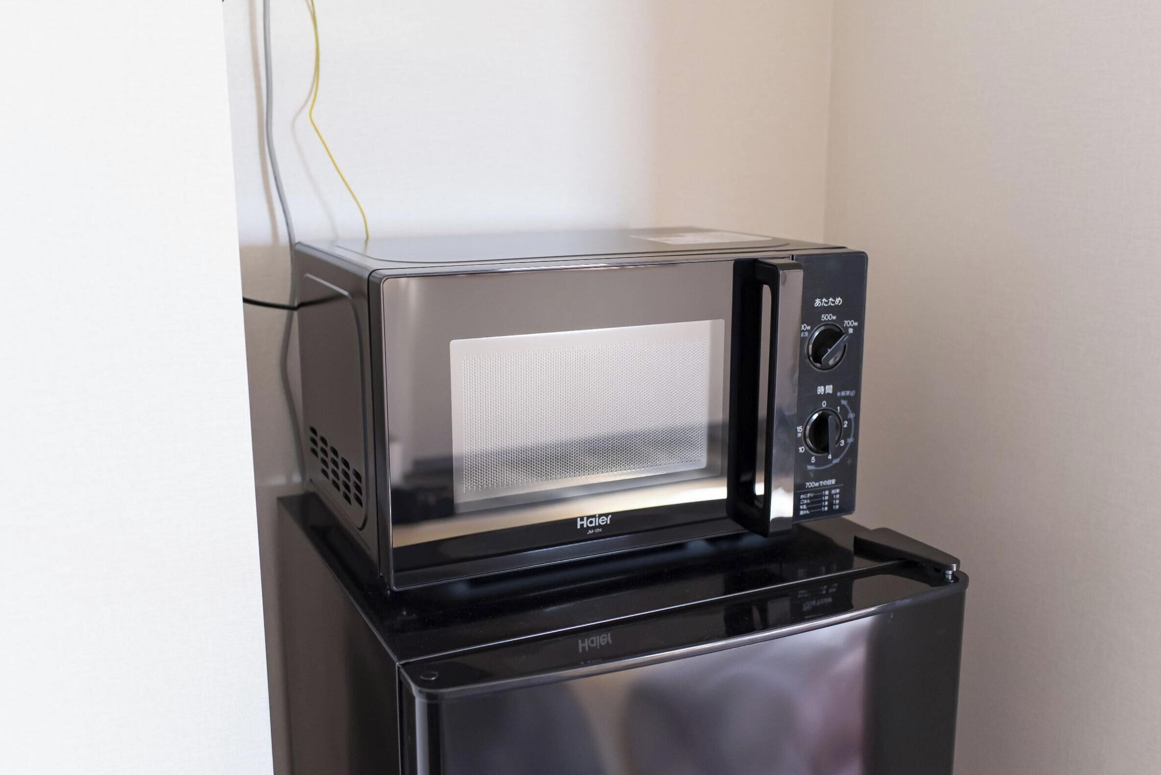 A compact microwave oven with a digital display and control panel, placed on a black countertop.