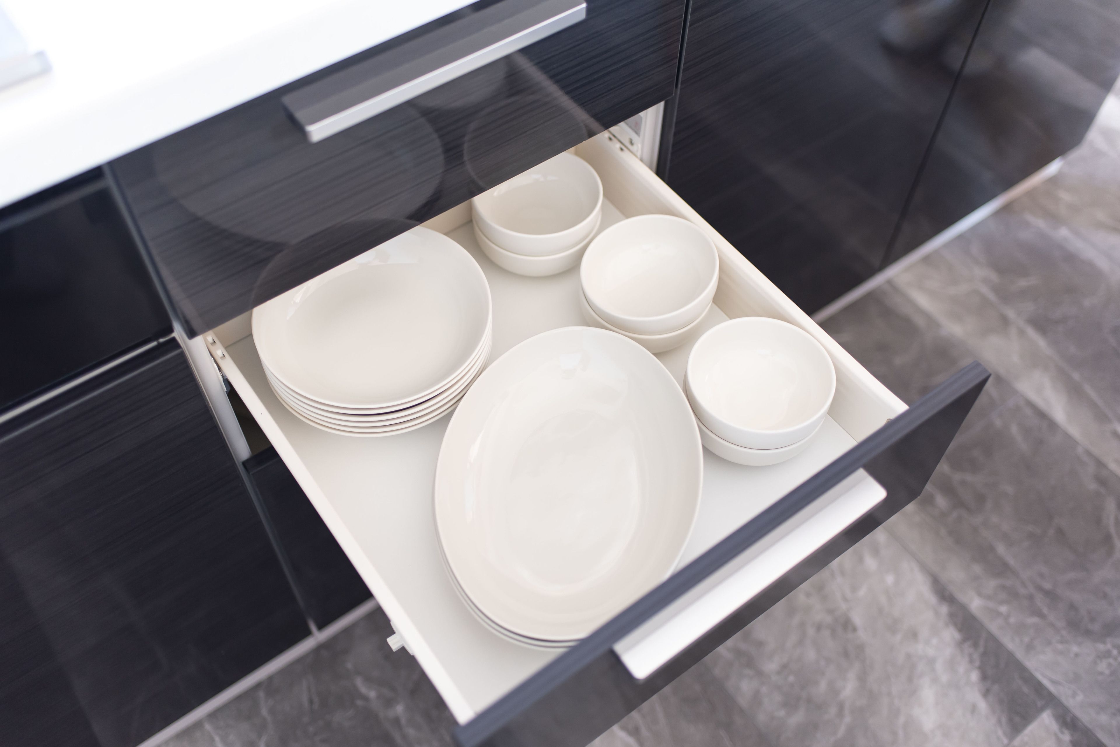 A kitchen drawer with white plates and bowls.