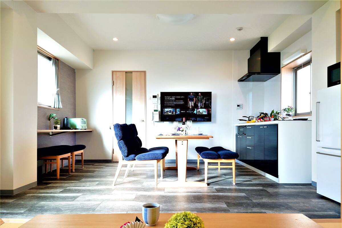 Una cocina moderna con comedor, que incluye una televisión de pantalla plana, un refrigerador y una cafetera.