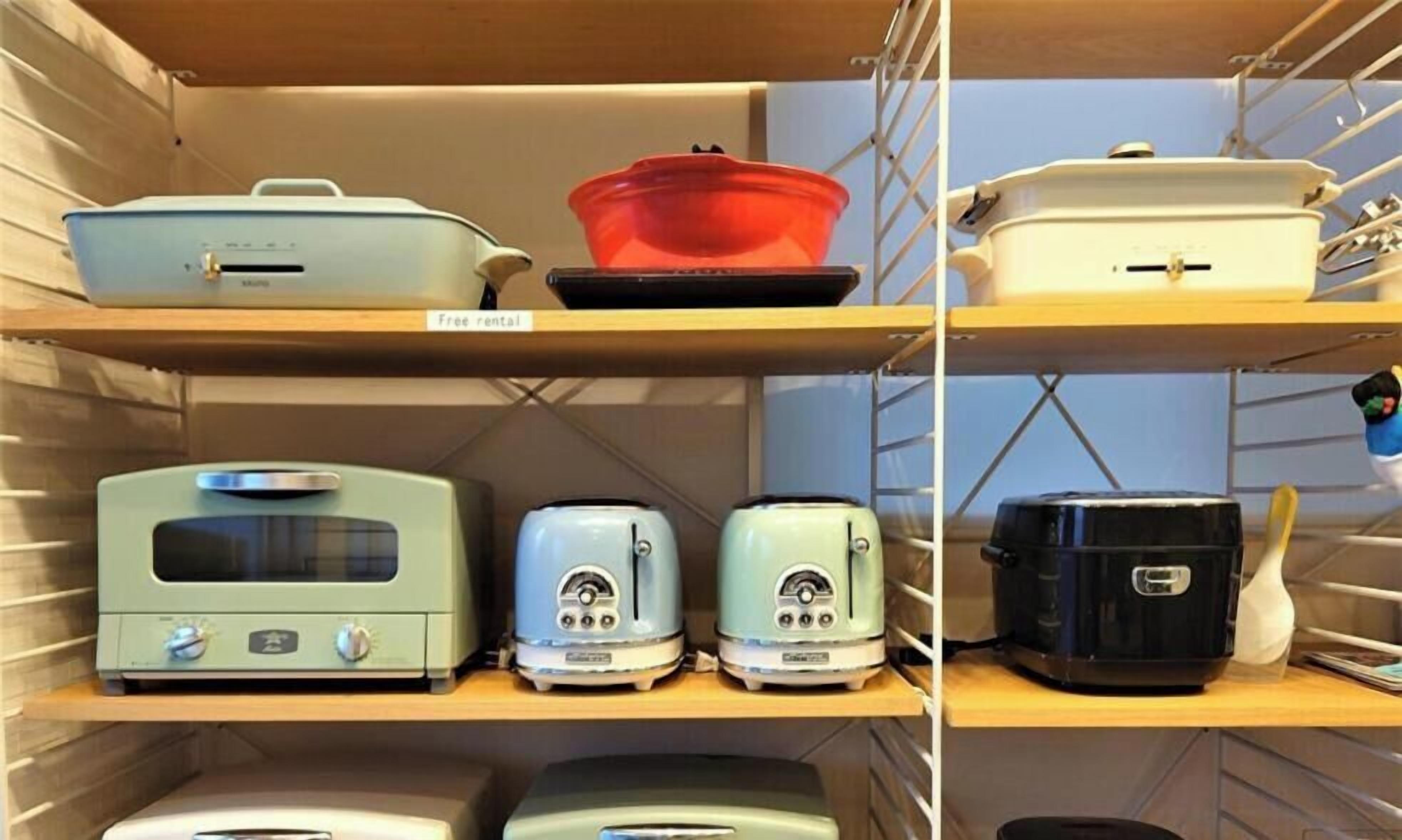 A kitchen with various appliances on shelves, including a toaster, a kettle, and a rice cooker.