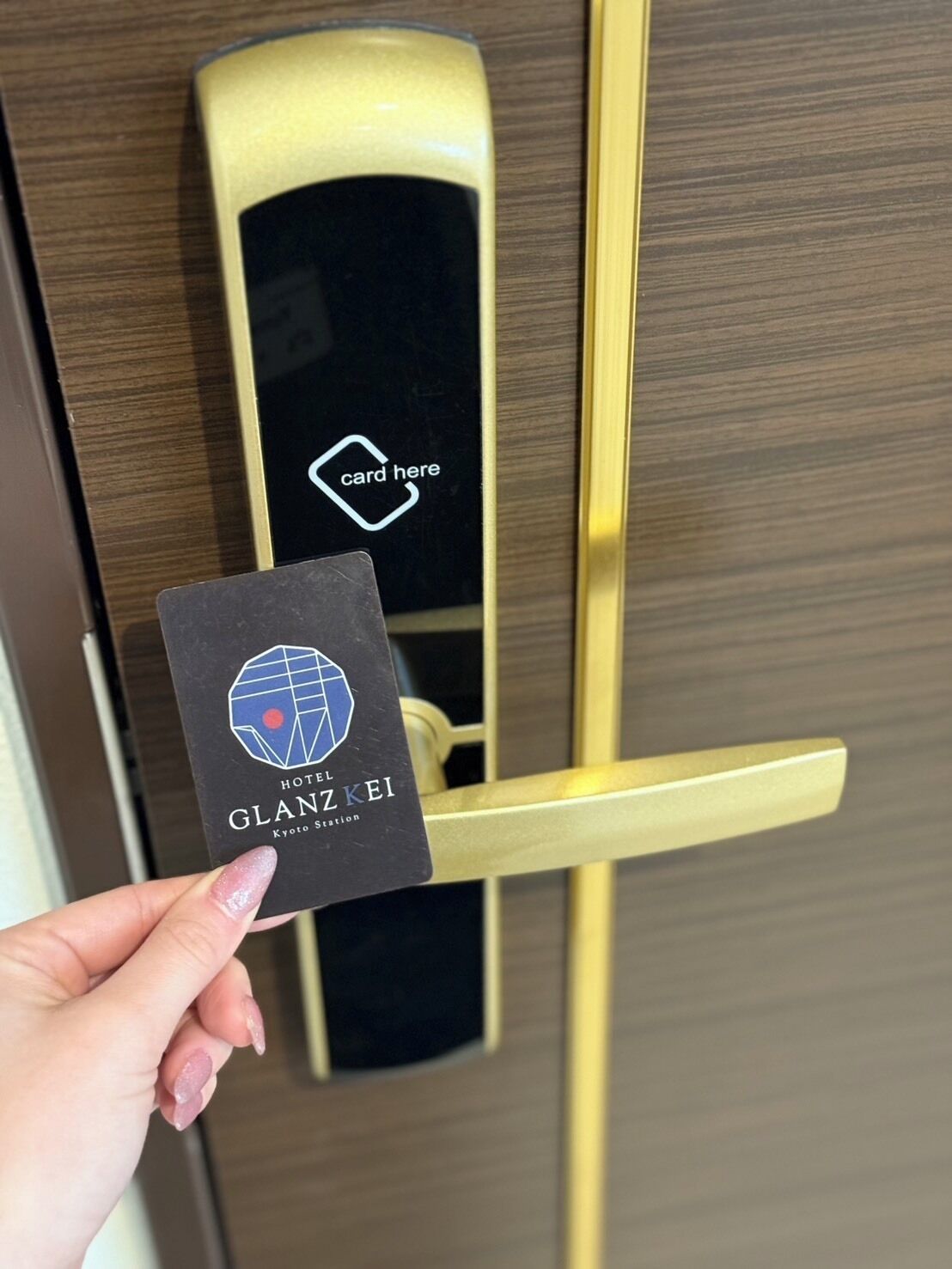 A hand holding a hotel card for Hotel Glanzke Kyoto Station.