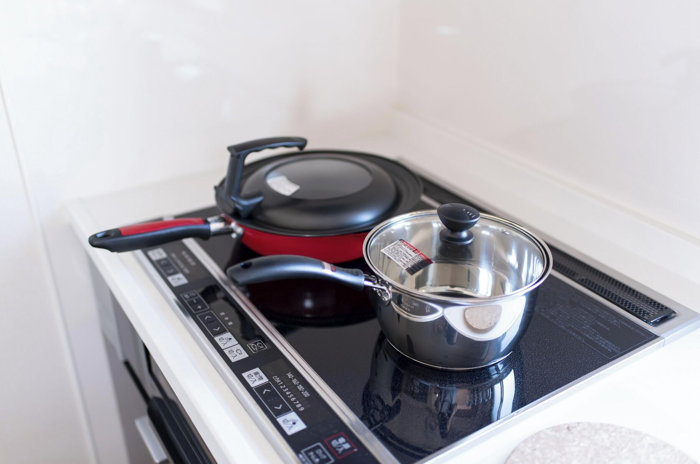 Een keuken met een fornuis, een rode pan en een pan op het fornuis.