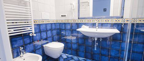 Un baño con lavamanos y váter blancos, y una zona de ducha.